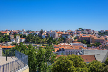 Fototapeta premium Panoramic view of Lisbon cityscape, showcasing terracotta rooftops, traditional and modern architecture under a clear blue sky. Lisbon, Portugal. 
