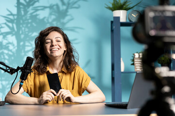 Smiling tech expert using professional camera to film technology review of new cellphone, doing unboxing video. Happy content creator showing phone box to subscribers, recording with high tech gear