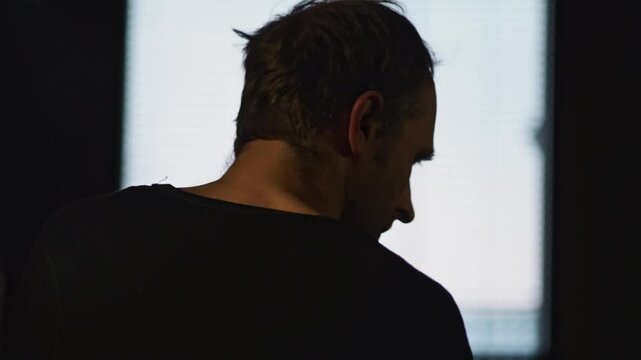 Silhouette of a man engaged in a phone conversation while facing a bright window. The image conveys a sense of privacy, anonymity, and perhaps contemplation or focus on the call
