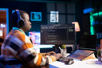 Black software engineer writes complex binary code scripts on computer, cybersecurity. Teleworking IT specialist in home office using programming language to safeguard consumer data.
