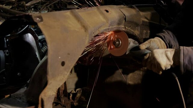 Working with angle grinder to fix metal body.male worker cuts metal  car body, car body repair.The car is rusting in a junkyard. Scrap metal that is disposed of.slow motion 4k