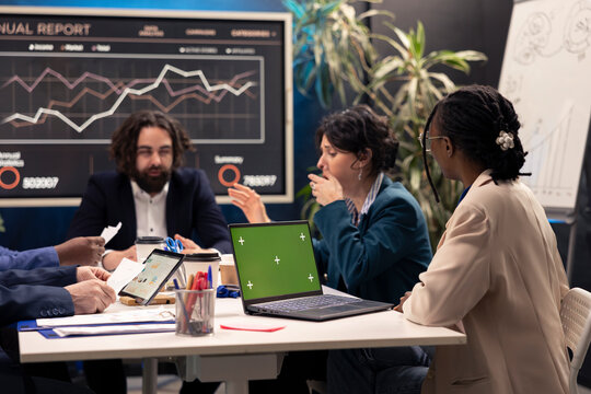Business associates attending conference next to greenscreen laptop, deciding the fate of the global organization and working on developing resources. Operations team addressing daily issues.