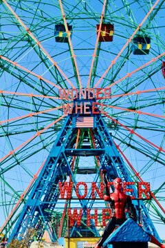 Coney Island, NYC, USA - August the 19th of 2022: Main view of Luna Park's iconic ferris wheel with a Spiderman toy on foreground. This Marvel Comics superhero was raised by his uncles in NYC.