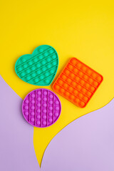 Set of trendy sensory play things on yellow background. Different shaped antistress children game. Colorful sensory silicone toys with push bubbles
