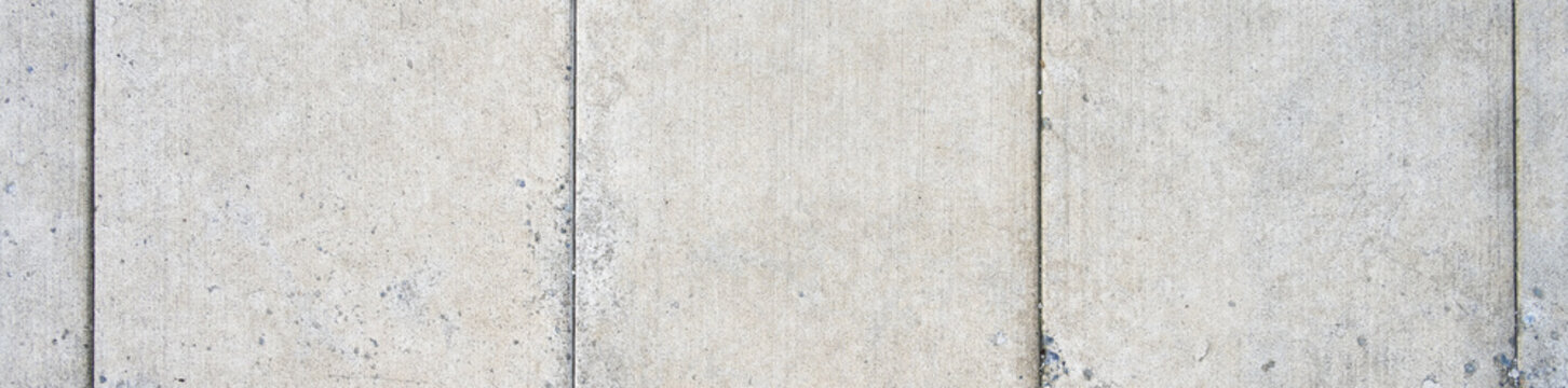 New cement sidewalk weathered and worn with aggregate rocks showing through the erosion, as a gray textured background
