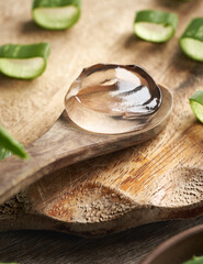 Aloe vera gel on a wooden spoon with fresh sliced leaves
