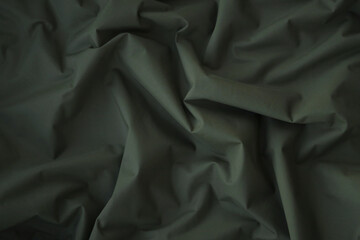 Texture of Dark green military uniform textile cloth with folds