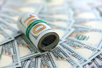 Roll of hundred dollar bills USD banknotes lies on big amount of united states money