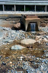 Small Waterfall Flowing Over Gravel from Concrete Block with Gully
