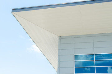 The exterior corner of a modern building with a flat roof, grey eave, white soffit, and...