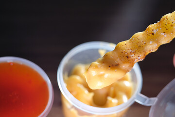 Dip crinkle cut fries in cheese sauce