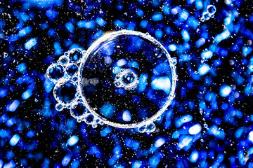 Close Up Macro of Oil and Water Bubbles Over Blue Glitter Background Design