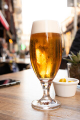 glass of craft beer served on a pub table with olives in the city center on a restaurant table