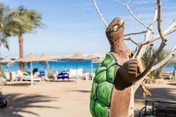 Tropical beach scene with turtle sculpture and palm trees by ocean