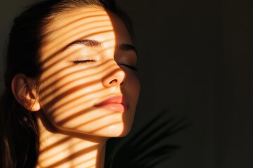 Obraz premium A peaceful woman with closed eyes basks in warm sunlight casting dramatic shadows, creating a serene and reflective atmosphere. The play of light is captivating.