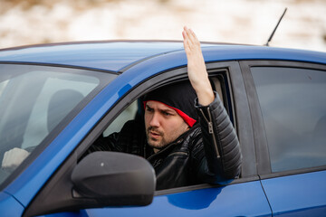An irritated young man driving a vehicle is expressing his road rage.