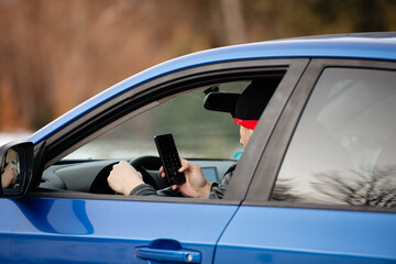 Man looking at mobile phone while driving a car.