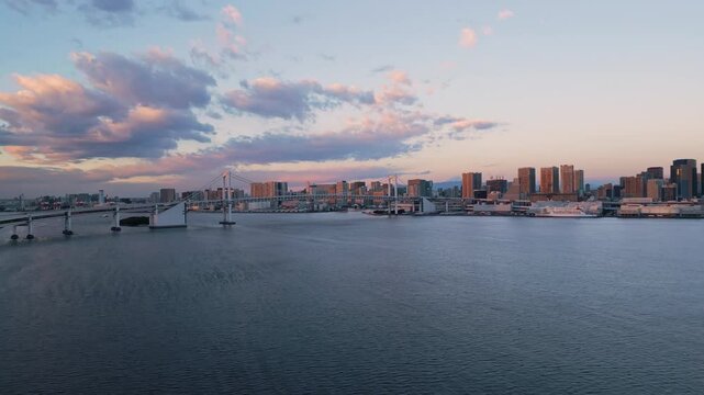 tokyo city skyline aerial view drone flying up over bay at dawn,rainbow bridge and town waterfront in the background