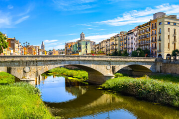 The stone bridge Pont de Pedra and the colorful yellow and orange houses in Girona, Catalonia, Spain.
