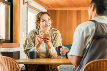 コテージ・キャビン・ログハウスでコーヒーを飲みながら笑顔で会話する夫婦
