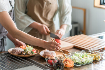 料理教室・クッキングスクールで料理を教える講師の女性と生徒の女性

