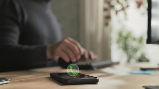 person at computer receiving phone call on smartphone mobile,male employee at the desk receives phonecall,icon symbol showing on the screen