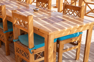 Sunlit wooden dining set on patio with cushions for outdoor gatherings