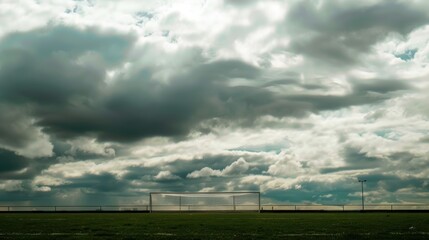 Obraz premium Dramatic Cloudy Sky Over a Soccer Goal on a Green Field