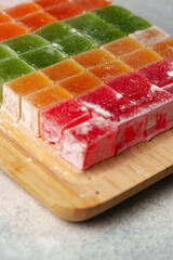 Colorful gelatins arranged neatly on a wooden cutting board in a bright kitchen setting