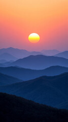 Fototapeta premium Misty mountains bathed in warm orange and yellow hues at sunset, symbolizing tranquility and the beauty of nature's chaos, a perfect high-definition phone wallpaper to evoke peace and awe