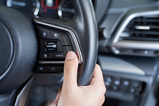 Woman's hand presses the button on the steering wheel of the car close-up. Multi function buttons