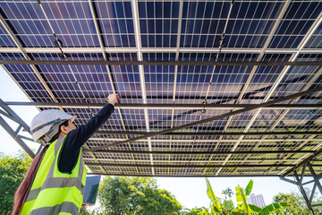 Engineer inspecting solar panels under a solar-powered carport on a sunny day, ensuring optimal...