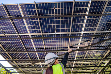 Engineer inspecting solar panels under a solar-powered carport on a sunny day, ensuring optimal...