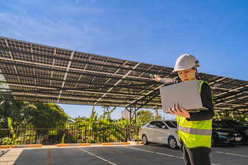 Engineer inspecting solar panels under a solar-powered carport on a sunny day, ensuring optimal...