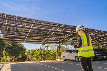 Engineer inspecting solar panels under a solar-powered carport on a sunny day, ensuring optimal...