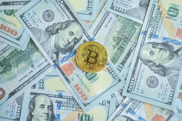 A Bitcoin token placed on America one hundred dollars banknote. Bitcoin is a digital currency which operates free of any central control or the oversight of banks or governments.