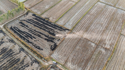 Aerial view of farmer burning rice paddy straws because it is a cheaper and easier option to...