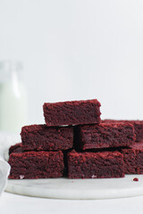 Overhead view of fudgy red velvet brownies on a white marble tray, top view of red velvet fudge brownies on a white background