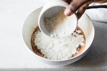 Overhead view of flour being added to madeleine batter, mixing flour into batter, process of making...