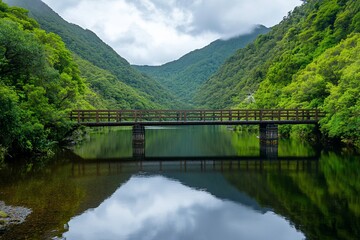 Scenic wooden bridge over a tranquil river surrounded by mountains.