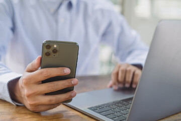 Business man using mobile phone and working on laptop computer at office. Man freelancer online working, surfing the internet at coffee shop, distance job, telework, remotely work, telecommuting