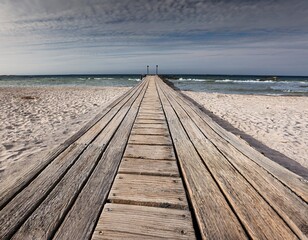 Tranquil Beachscape: Wooden Pier Connecting Sand and Ocean Waters