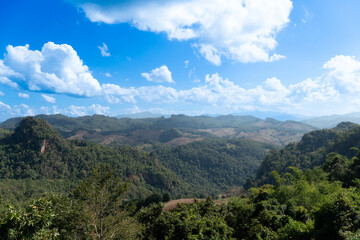 landscape of rolling green hills and valleys under a bright blue sky with scattered white clouds. Landmark hills of village Ban Jabo. Mae Hong Son of Thailand.