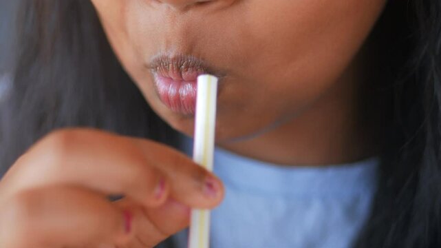 Little girl drinking soft drinks with a plastic straw 