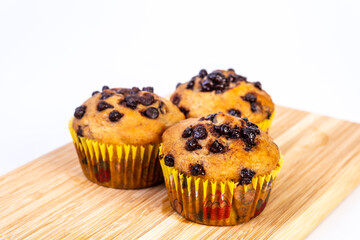 Banana chocolate chip muffins on wooden board. Breakfast or snack recipe idea.