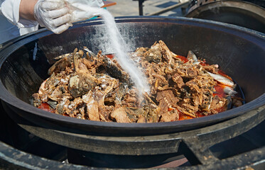 Freshly caught wild fish soup cooked in an outdoor wood-fired iron pot