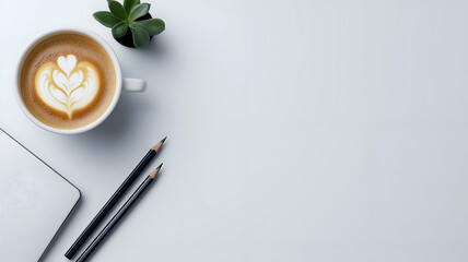 Flat lay of a coffee cup with latte art on a clean white desk, featuring pencils and a notebook for a calming and elegant workspace