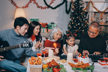 Multi-Generation Family Celebrate Christmas At Home Wearing Santa Hats And Antlers Opening Presents