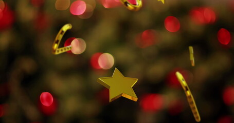 Fototapeta premium Image of christmas gold stars and candy canes falling over flickering fairy lights