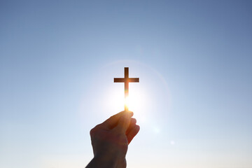 Lifting the cross of Jesus Christ toward the bright sunrise sunlight. Hopeful New Year and bright...